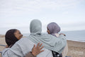Three Muslim friends embracing on beach
