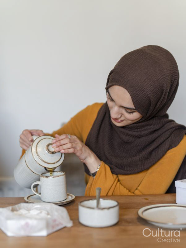 Woman pouring tea to cup at home