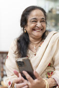 Portrait of senior woman laughing while using smart phone in living room