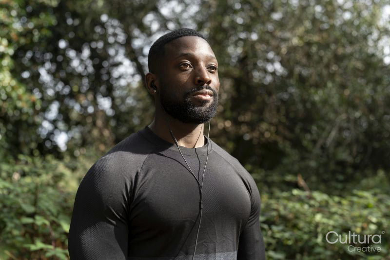 Portrait of athletic man with earbuds standing in park