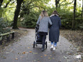 Back view of couple walking in park with stroller