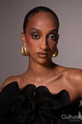 Woman in a black dress with gold earrings on a grey background