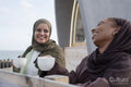 Two Muslim women drinking coffee in sidewalk cafe