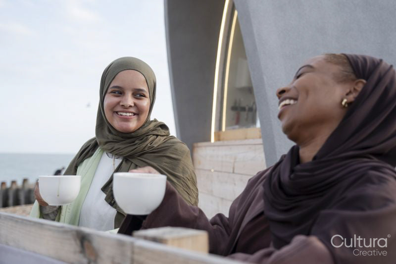 Two Muslim women drinking coffee in sidewalk cafe