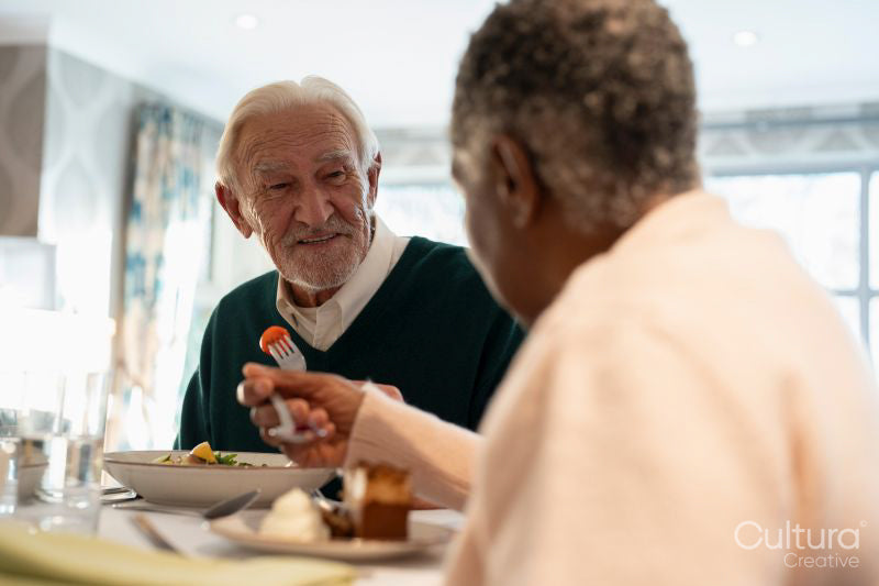 Smiling senior people eating meal in nursing home