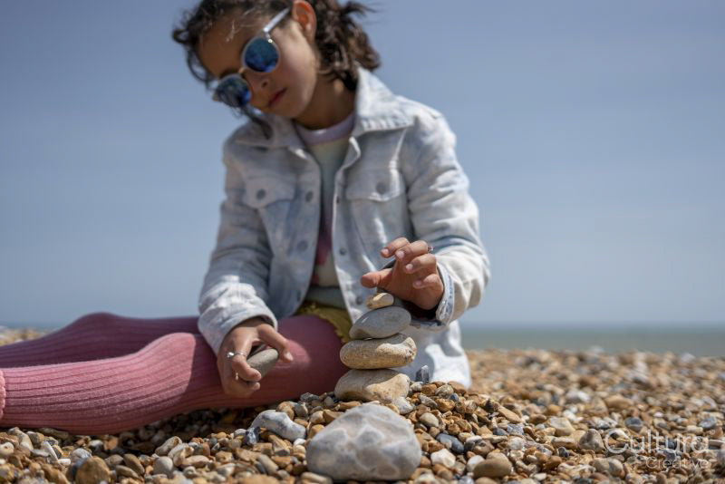 Girl stacking stones on beach