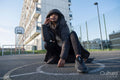 Portrait of woman in overcoat with hood sitting on basketball court