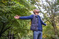 Man standing in forest, stretching arms and looking up