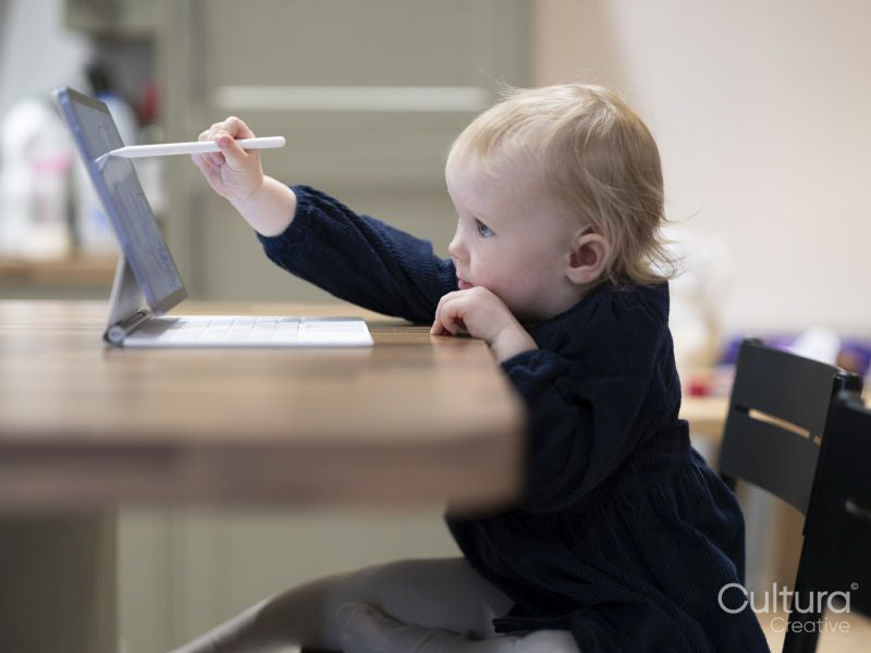 Girl with hearing aid drawing on digital tablet at table