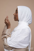 Studio shot of young woman in white hijab praying