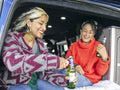 Women sitting in back of van and opening beer