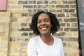 Portrait of smiling woman against brick wall