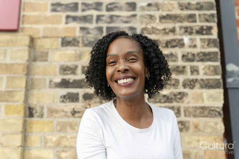 Portrait of smiling woman against brick wall