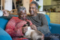 Senior couple with cat sitting on sofa