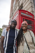 Happy mature couple posing in front of traditional red telephone booth