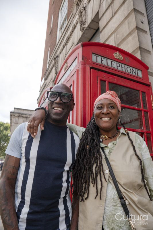 Happy mature couple posing in front of traditional red telephone booth