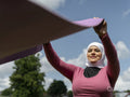 Sutton,Woman in headscarf unrolling yoga mat outdoors