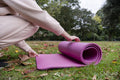 Close-up of woman unrolling yoga mat on grass in park