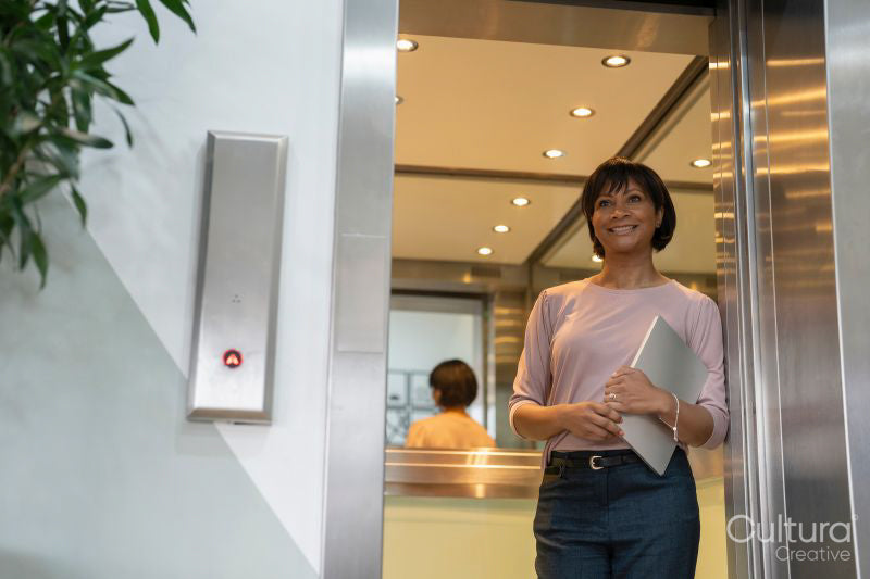 Businesswoman walking out of elevator in office