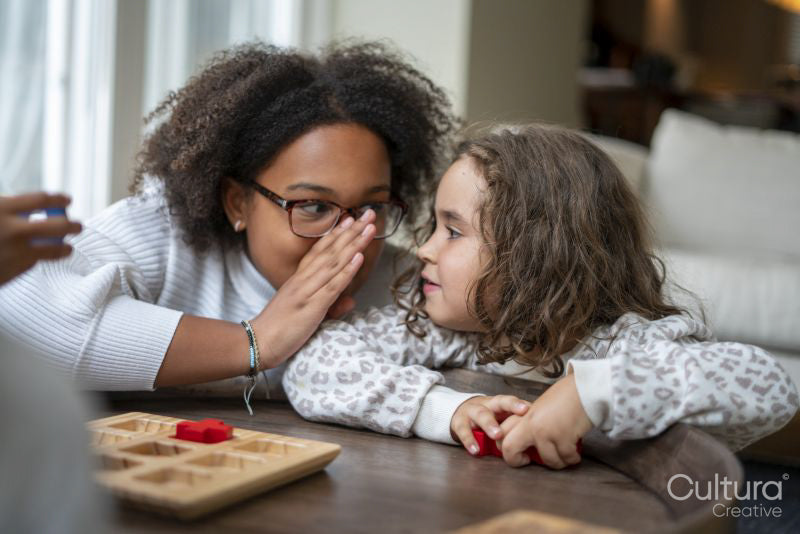 Girl whispering to sisters ear at home