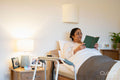 Senior lady reading book in bed at nursing home