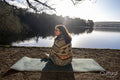 Young woman sitting on yoga mat at lake
