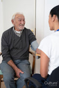 Female doctor taking senior patients blood pressure in office