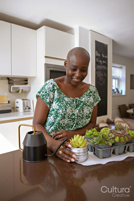 Woman potting plant in kitchen