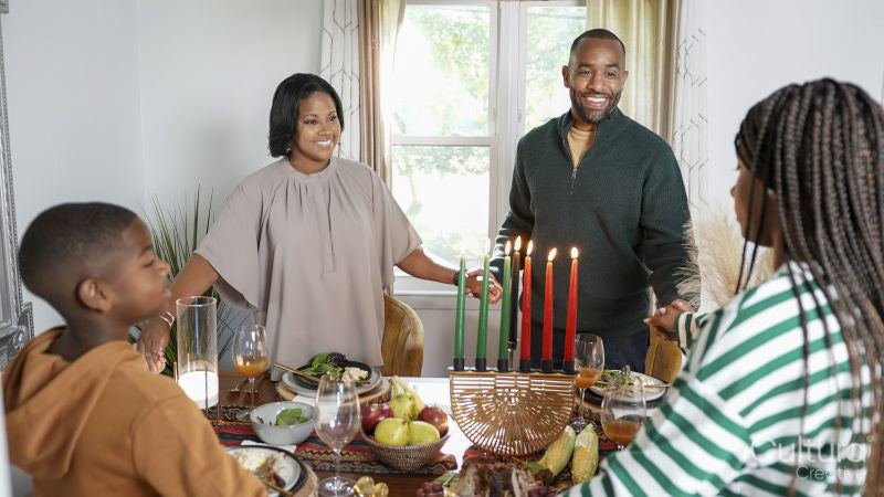 Family with children holding hands over Kwanzaa meal