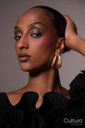 Woman in a black dress with gold earrings on a grey background