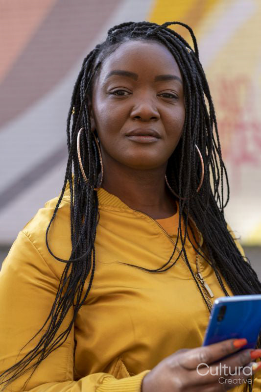 South Yorkshire, Portrait of woman with braided hair holding smart phone