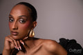 Woman in a black dress with gold earrings on a grey background