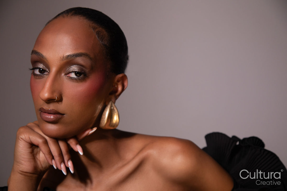 Woman in a black dress with gold earrings on a grey background