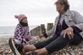 Grandmother and granddaughter sitting on beach on cloudy day