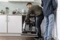 Male couple unloading dishwasher at home