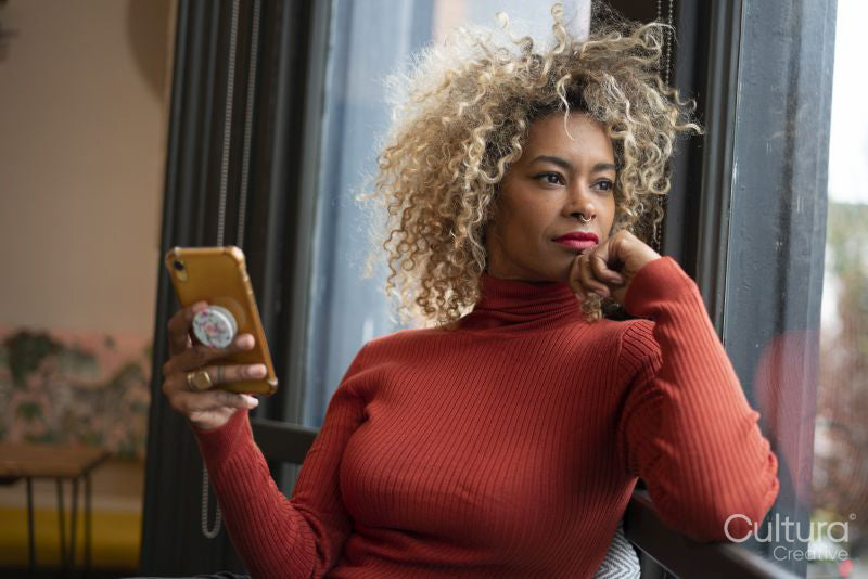 Woman using smart phone and looking through window