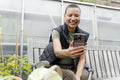 Smiling woman photographing harvested vegetables with smart phone