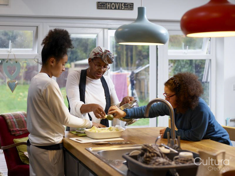 Mother with two daughters preparing food in kitchen