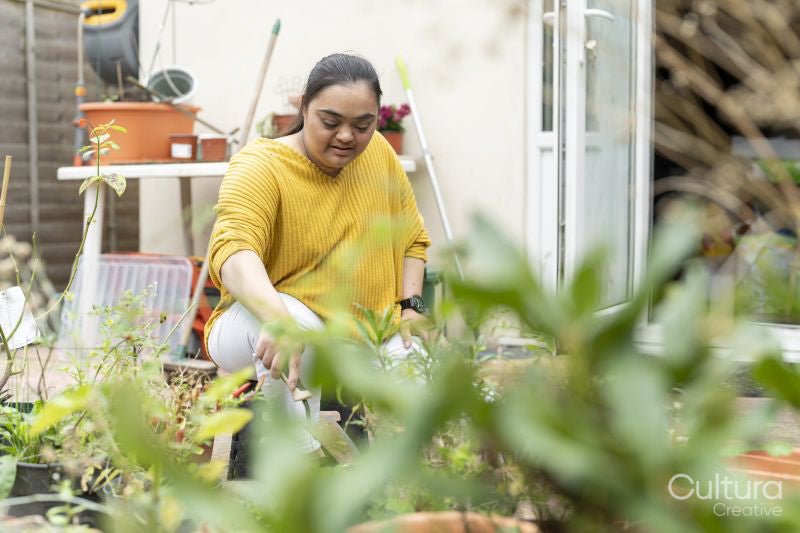 Young woman with down syndrome planting flowers in garden
