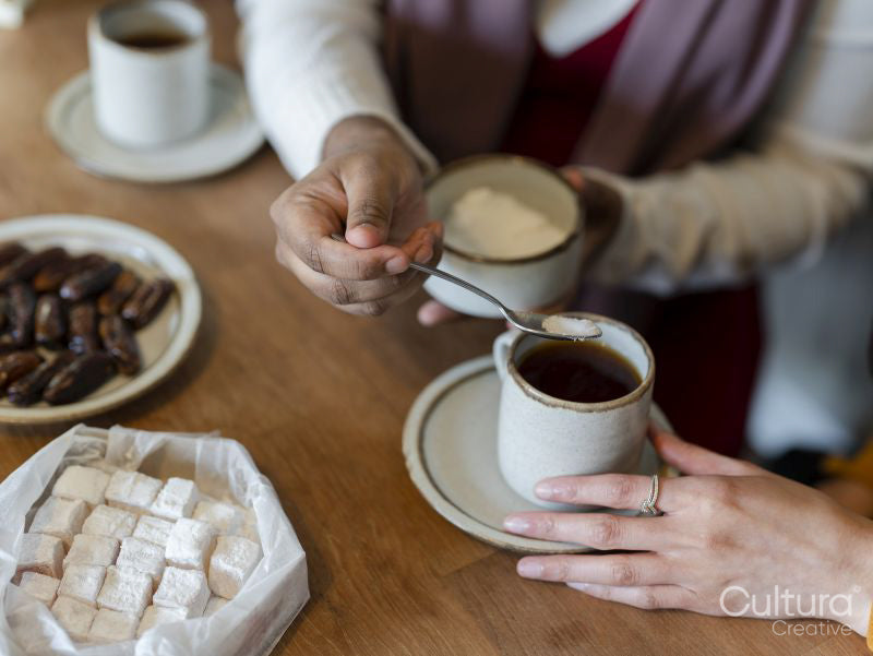 Woman adding sugar to friends tea