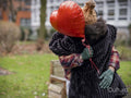 Couple with red heart shaped balloon hugging outdoors
