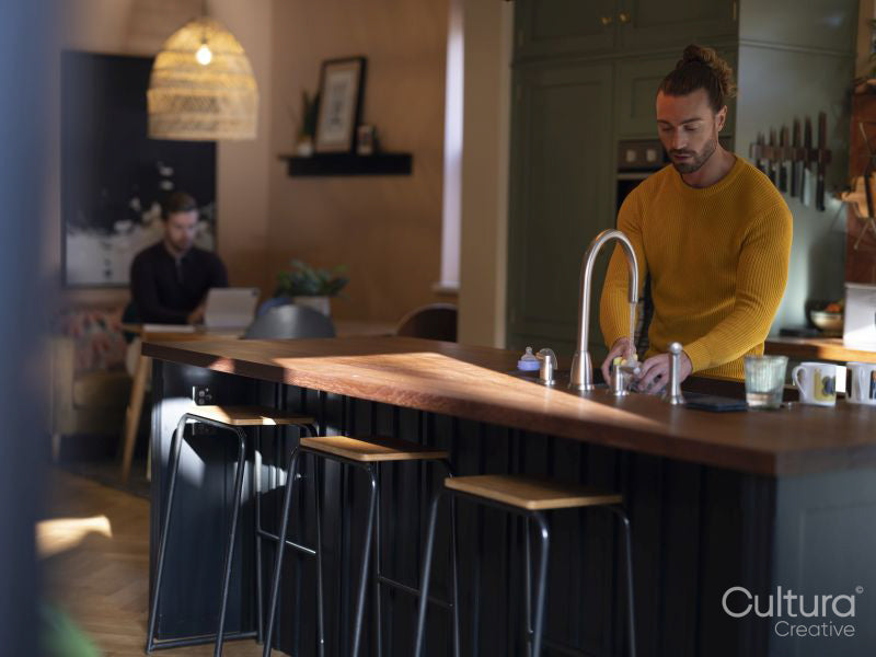 Man washing dishes while boyfriend using digital tablet at home kitchen