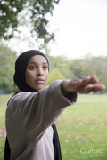 Portrait of woman in hijab in yoga warrior pose in park