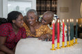 Teenage girl with mother and grandmother at table with Kwanzaa candles