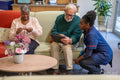 Smiling nurse helping senior man use tablet in nursing home