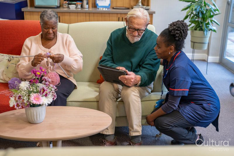 Smiling nurse helping senior man use tablet in nursing home