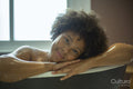 Portrait of smiling woman leaning on edge of bathtub
