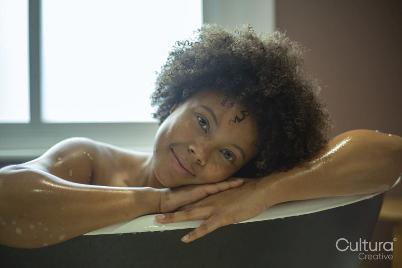 Portrait of smiling woman leaning on edge of bathtub