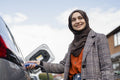 Woman wearing hijab charging electric car