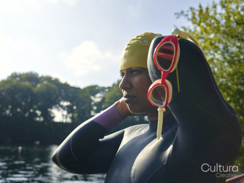 Woman in wetsuit putting on swimming cap